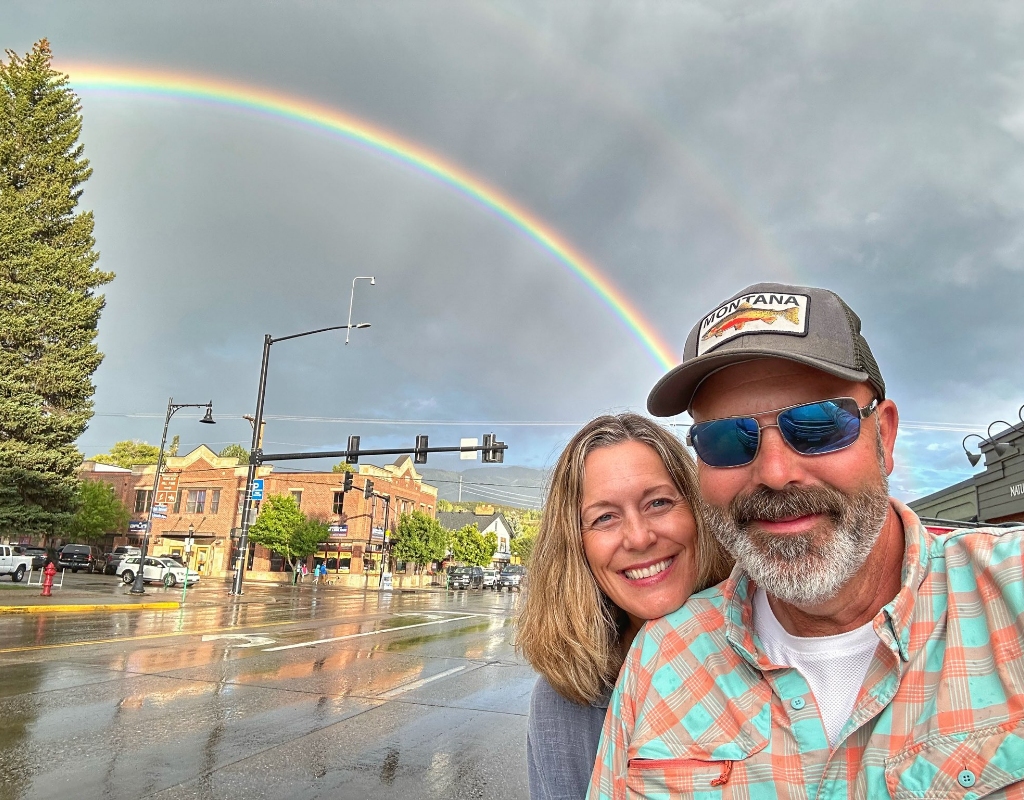 Ryan Busse taking a selfie with his wife infront of a rainbow