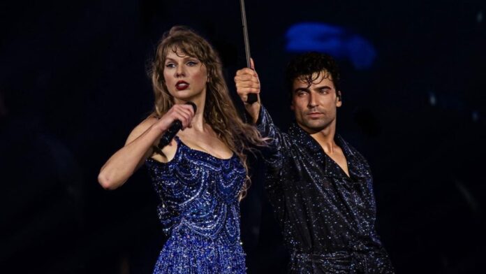 Jan Ravnik holding an umbrella over Taylor Swift on stage