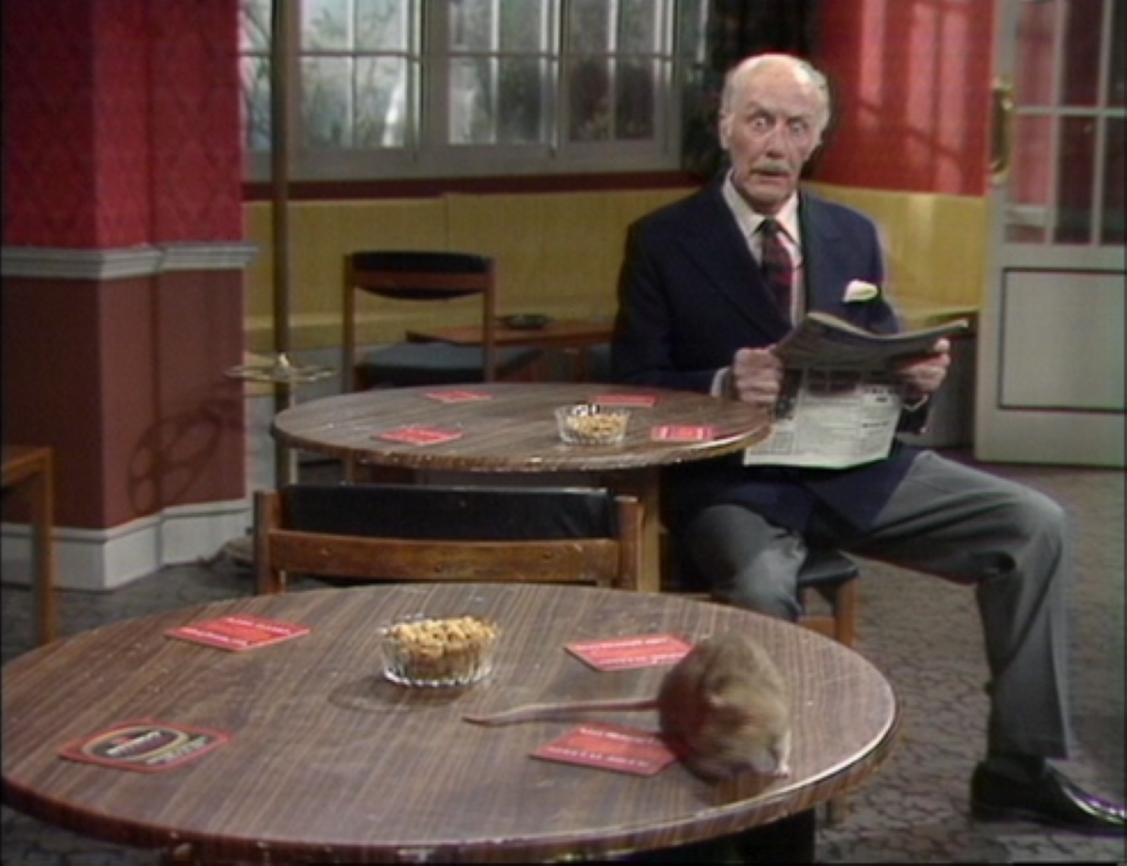 A person reading newspaper by sitting on a chair in Fawlty Towers, “The Anniversary” and “Basil the Rat”