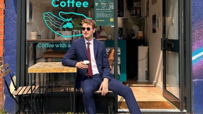 Chris Jenks wearing a blue suit holding his coffee cup.