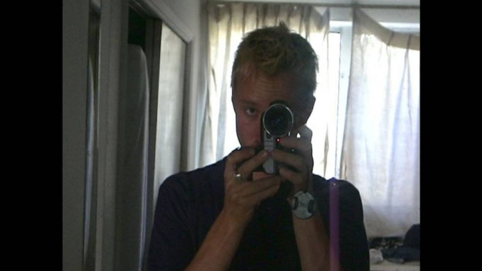 Daniel holding his camera taking a mirror selfie.