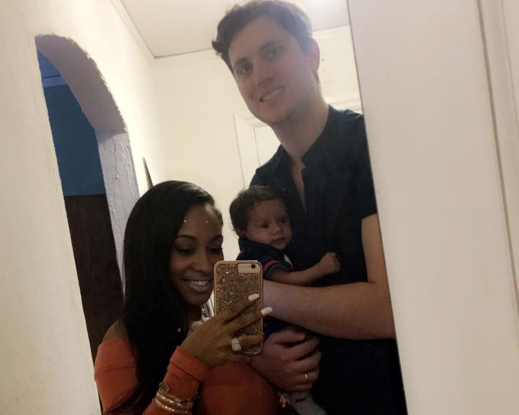 Nakira taking a mirror selfie with her husband and son.