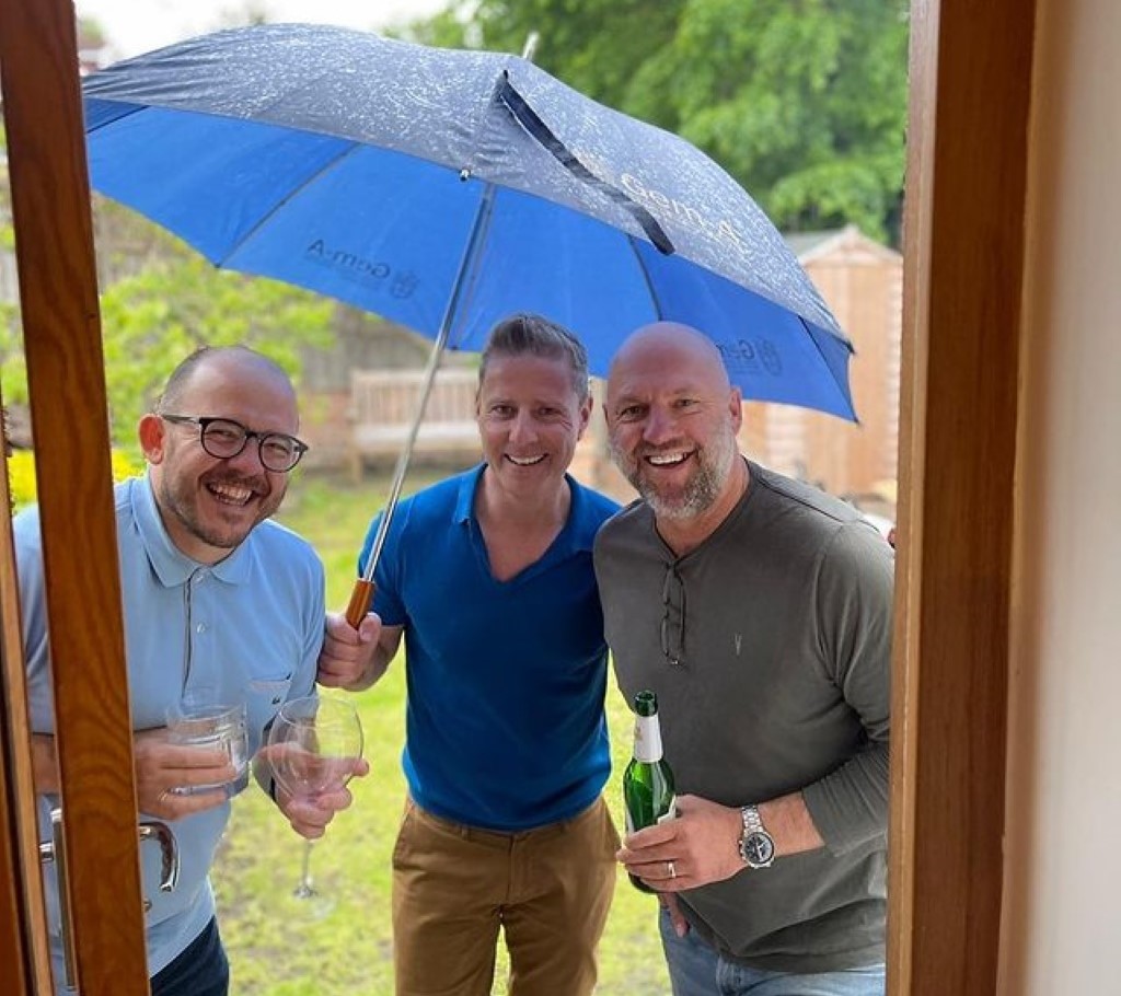 Matt Slack with his friends carrying blue umbrella.