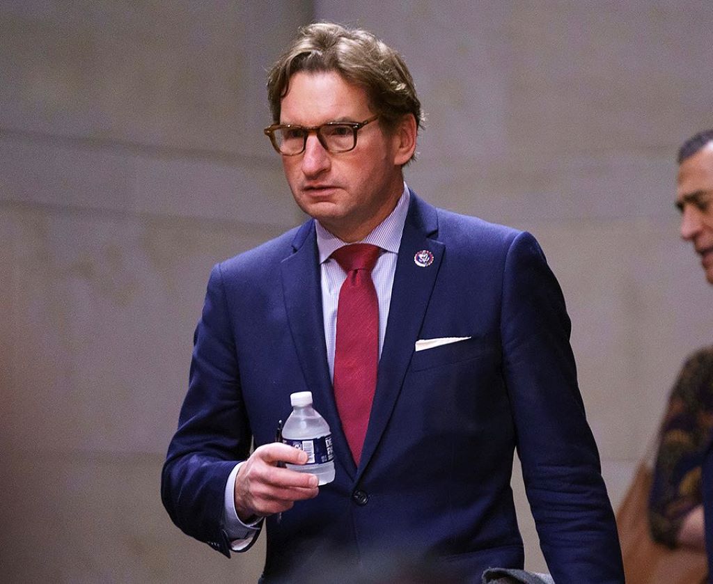 Dean phillips wearing a spectacles and holding a bottle