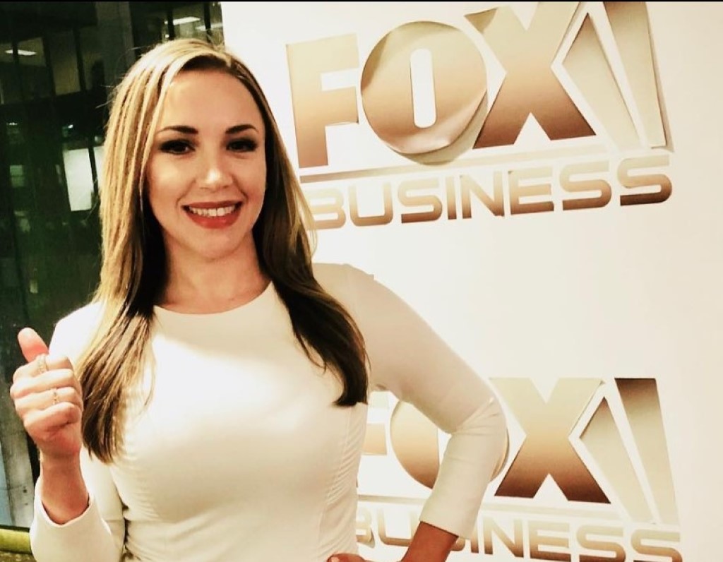 Hamill poses in a white dress in front of a Fox Business poster.
