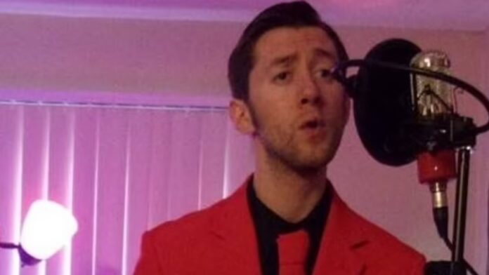 Justin, dressed in a red coat and red tie, sings into a microphone.