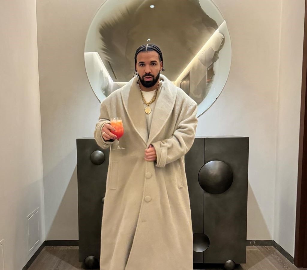 Drake wearing long coat holding juice
