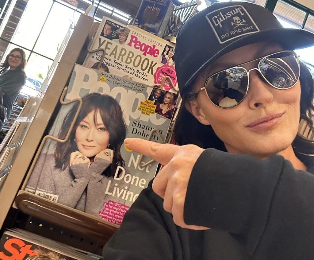 Shannen Doherty with pointing towards a magazine