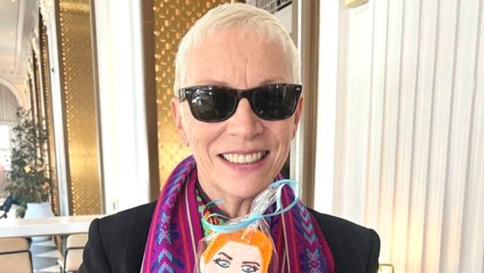 Annie Lennox, in black goggles, coat, and a purple-blue mixed scarf around her neck.